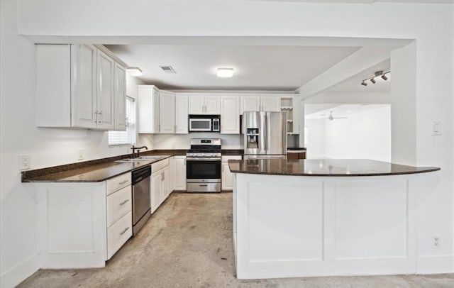 3818 Childress St, Houston, TX 77005 - kitchen featuring stainless steel appliances, white cabinets, unfinished concrete floors, and a peninsula