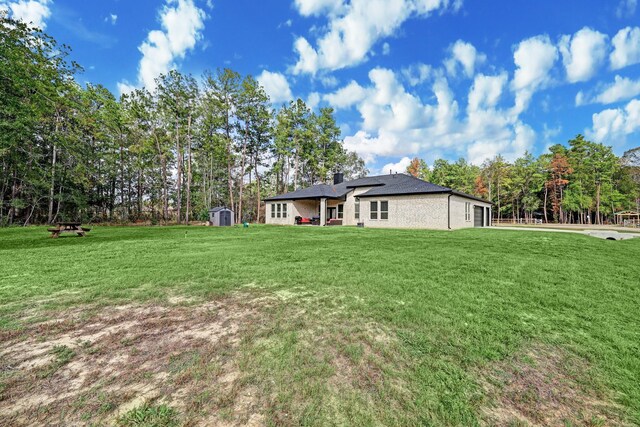 13 Rd 66111, Dayton, TX 77535 - back of property featuring a storage shed, a lawn, a garage, a chimney, and view of wooded area