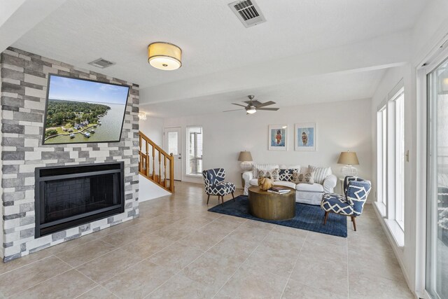 426 Apollo Dr, Livingston, TX 77351 - living area featuring light tile patterned floors, stairs, a ceiling fan, and a large fireplace