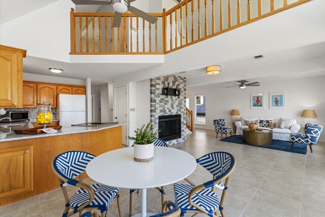 426 Apollo Dr, Livingston, TX 77351 - dining area with a ceiling fan, a towering ceiling, a fireplace, and light tile patterned flooring