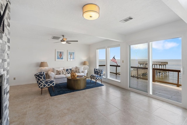 426 Apollo Dr, Livingston, TX 77351 - living room featuring a textured ceiling, a fireplace, light tile patterned floors, ceiling fan, and a water view