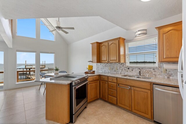 426 Apollo Dr, Livingston, TX 77351 - kitchen with appliances with stainless steel finishes, ceiling fan, a peninsula, plenty of natural light, and vaulted ceiling
