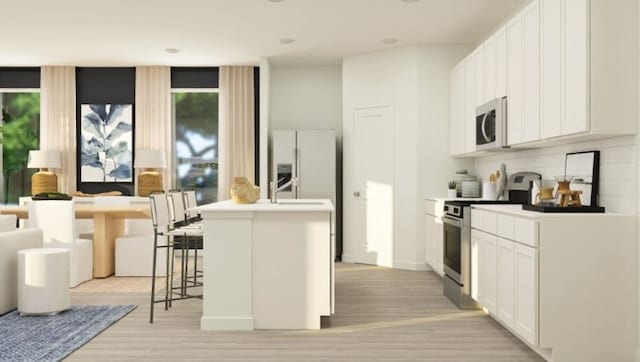 1203 Garrett Sudhendrio Dr, Crosby, TX 77532 - kitchen featuring appliances with stainless steel finishes, light wood finished floors, an island with sink, and white cabinets