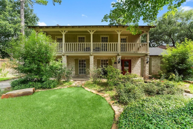 27277 Wells Ln, Conroe, TX 77385 - view of front facade with a balcony, brick siding, board and batten siding, and covered porch