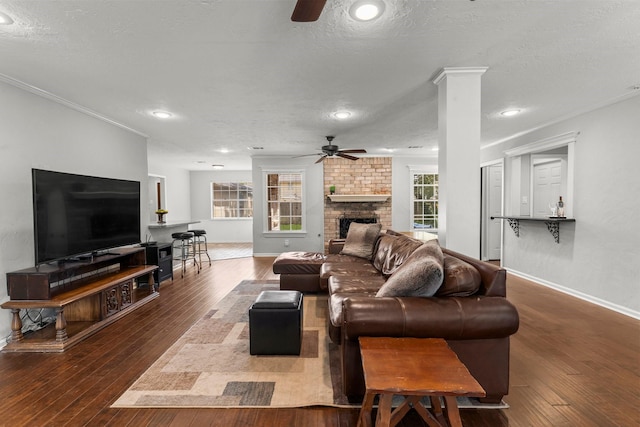 27277 Wells Ln, Conroe, TX 77385 - living room with ceiling fan, hardwood / wood-style floors, a brick fireplace, ornamental molding, and a textured ceiling