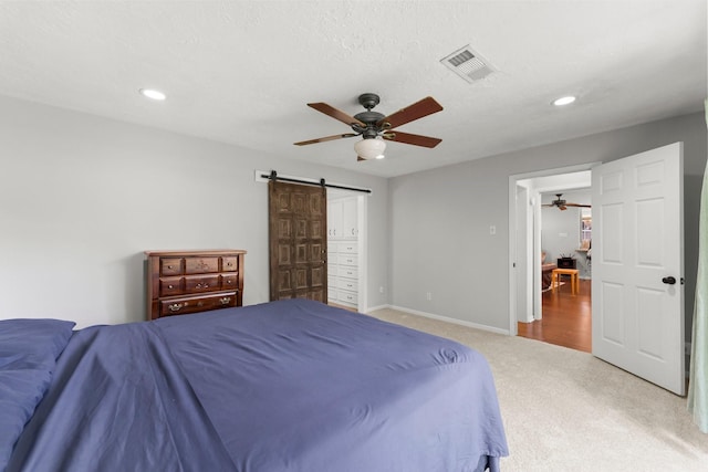 27277 Wells Ln, Conroe, TX 77385 - bedroom with a barn door, carpet floors, recessed lighting, and ceiling fan