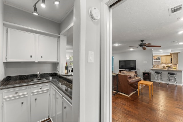 27277 Wells Ln, Conroe, TX 77385 - kitchen with white cabinets, ceiling fan, dark wood finished floors, dark stone counters, and a textured ceiling