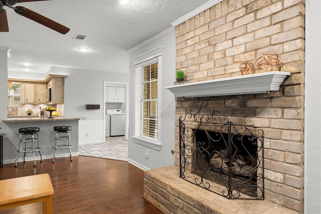 27277 Wells Ln, Conroe, TX 77385 - living area with washer / clothes dryer, a ceiling fan, crown molding, hardwood / wood-style floors, and a brick fireplace