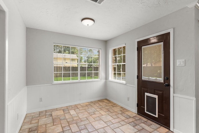 27277 Wells Ln, Conroe, TX 77385 - entryway featuring a wainscoted wall, a textured ceiling, and brick patterned floors