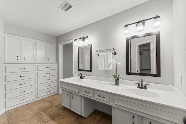 27277 Wells Ln, Conroe, TX 77385 - bathroom with double vanity, a textured ceiling, and stone finish flooring