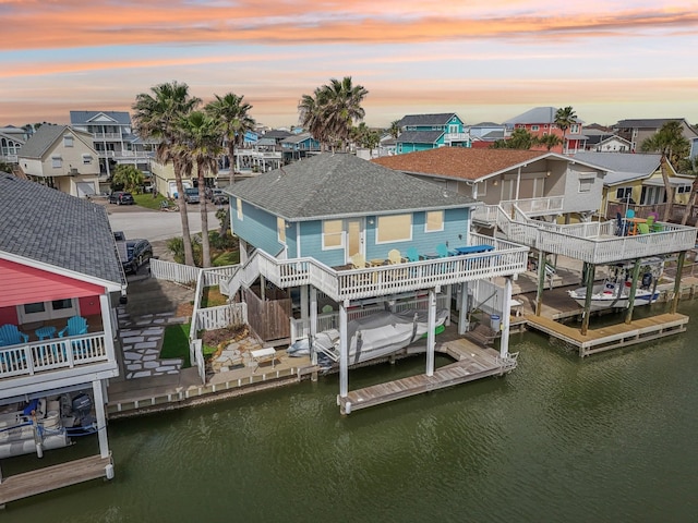 22123 Yoakum Dr, Galveston, TX 77554 - back of house with a residential view, a water view, boat lift, roof with shingles, and stairway