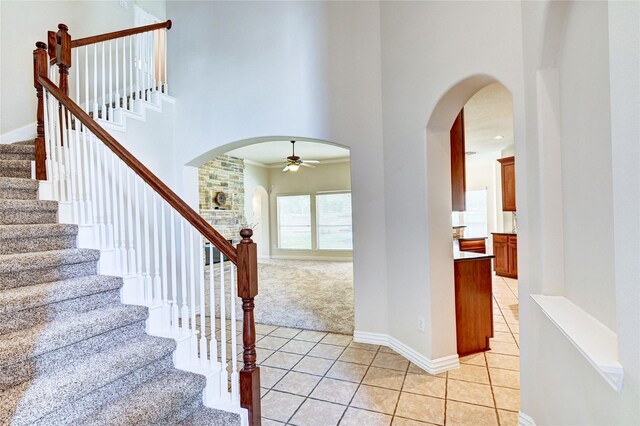 30 N Scribewood Cir, The Woodlands, TX 77382 - stairs featuring arched walkways, ceiling fan, tile patterned flooring, a towering ceiling, and carpet flooring
