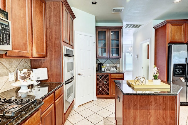 30 N Scribewood Cir, The Woodlands, TX 77382 - kitchen featuring appliances with stainless steel finishes, light tile patterned flooring, backsplash, dark stone counters, and recessed lighting