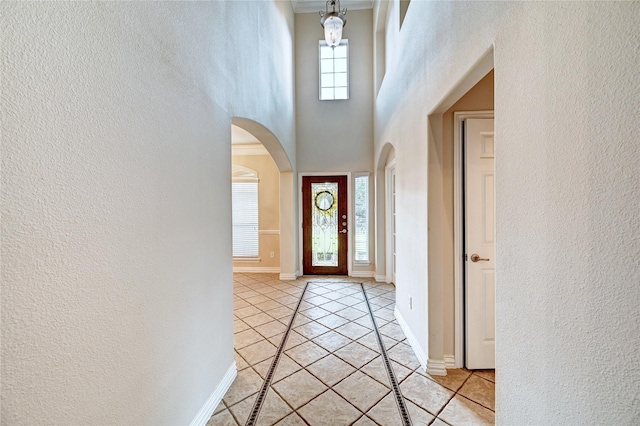 30 N Scribewood Cir, The Woodlands, TX 77382 - foyer with arched walkways, light tile patterned flooring, a textured wall, inlaid floor details, and a towering ceiling