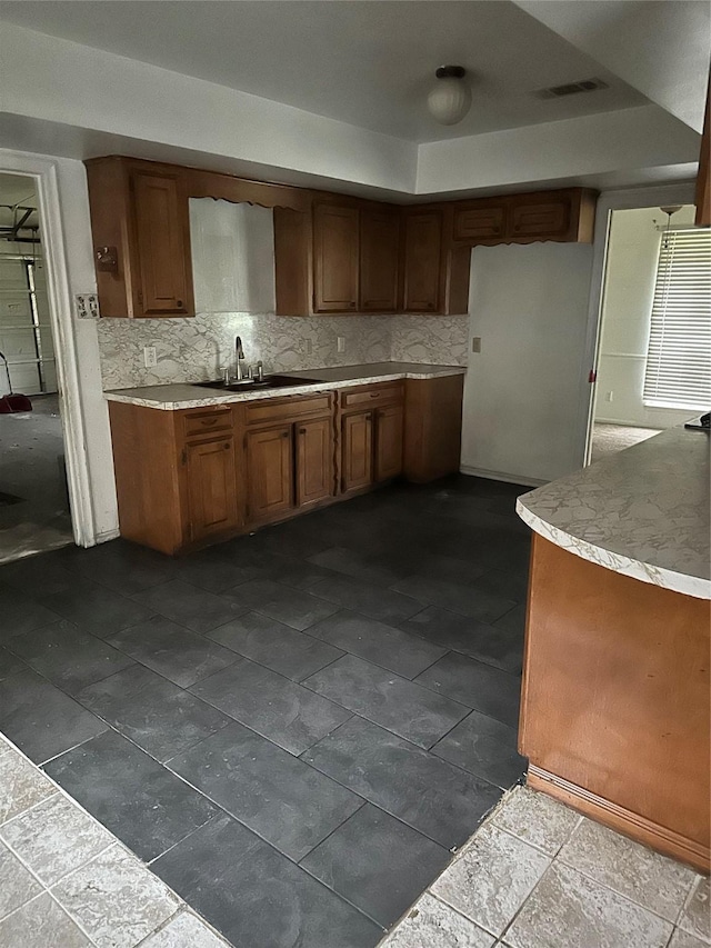 6646 Bayou View Dr, Houston, TX 77091 - kitchen featuring light countertops, decorative backsplash, and brown cabinetry