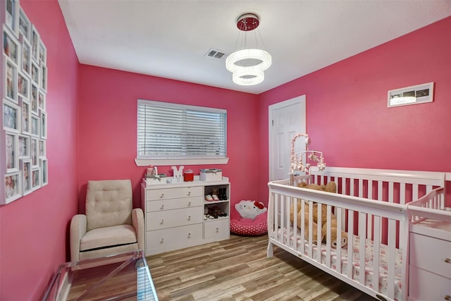 16806 Carbridge Dr, Houston, TX 77084 - bedroom featuring a chandelier, wood finished floors, and a crib