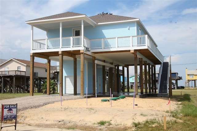 13214 Buccaneer Pkwy, Freeport, TX 77541 - rear view of property featuring a carport, driveway, an attached garage, roof with shingles, and a wooden deck