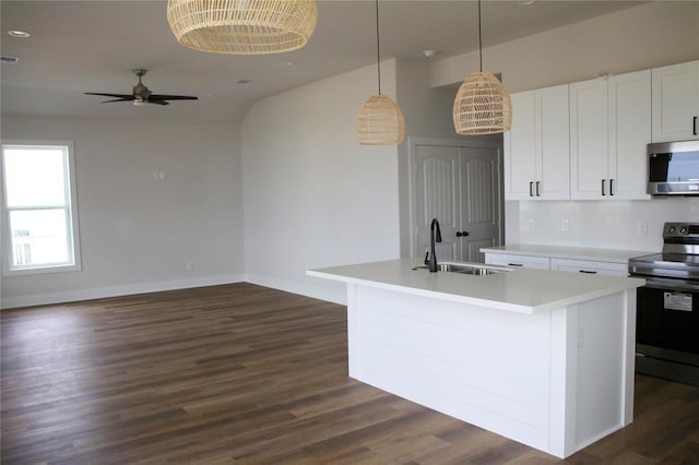 13214 Buccaneer Pkwy, Freeport, TX 77541 - kitchen featuring appliances with stainless steel finishes, a ceiling fan, dark wood finished floors, white cabinetry, and a center island with sink
