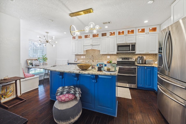 1880 White Oak Dr Unit 159, Houston, TX 77009 - kitchen featuring appliances with stainless steel finishes, a chandelier, blue cabinets, dark wood-style flooring, and a textured ceiling