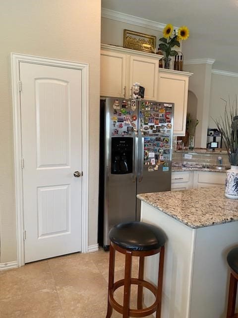 6727 Trinity Trail Ln, Richmond, TX 77469 - kitchen with stainless steel refrigerator with ice dispenser, ornamental molding, light stone countertops, a kitchen bar, and white cabinetry