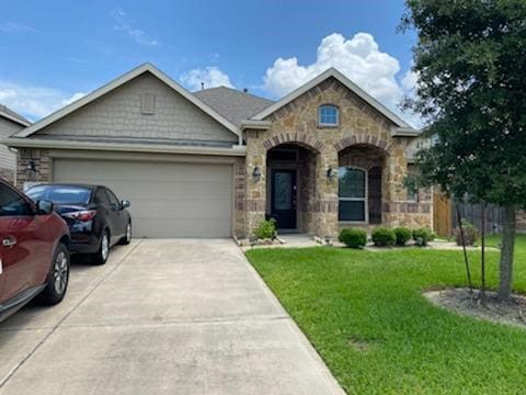 6727 Trinity Trail Ln, Richmond, TX 77469 - view of front facade featuring stone siding, an attached garage, and driveway