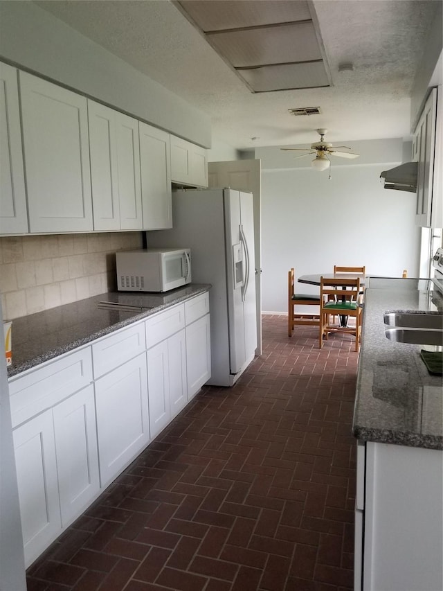 8806 Leader St, Houston, TX 77036 - kitchen featuring white appliances, white cabinetry, dark stone counters, and brick flooring