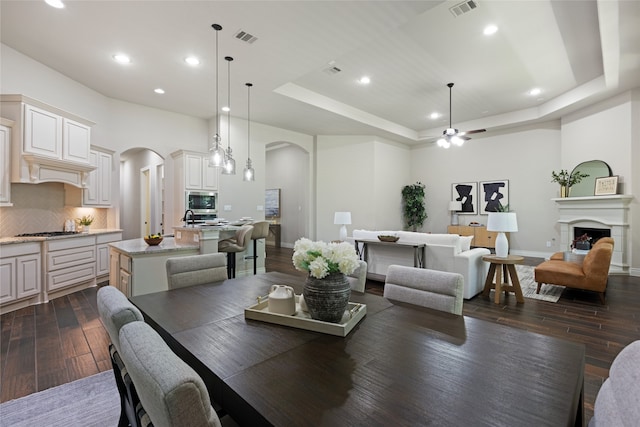 131 Evening Tide Ct, Conroe, TX 77318 - dining area featuring arched walkways, dark wood-style floors, a tray ceiling, recessed lighting, and ceiling fan