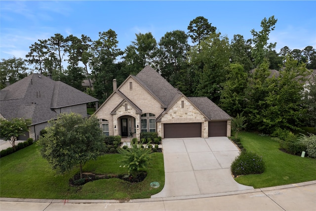131 Evening Tide Ct, Conroe, TX 77318 - french country style house featuring an attached garage, driveway, stone siding, and a front yard