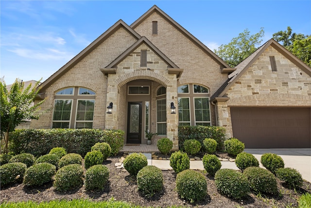 131 Evening Tide Ct, Conroe, TX 77318 - french country inspired facade with brick siding, an attached garage, concrete driveway, and stone siding
