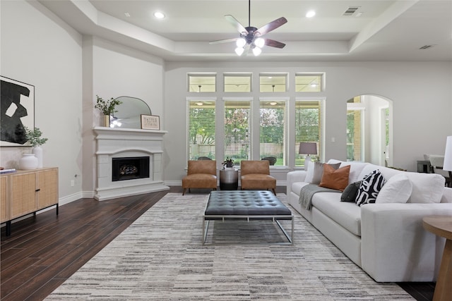 131 Evening Tide Ct, Conroe, TX 77318 - living area with a raised ceiling, a ceiling fan, wood finished floors, a fireplace with raised hearth, and arched walkways
