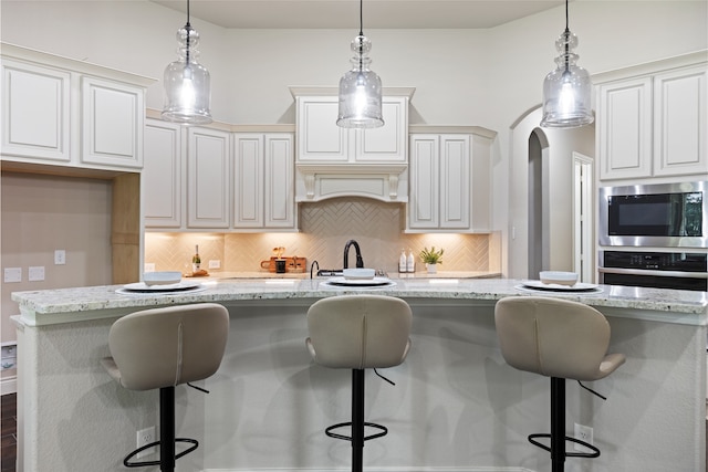 131 Evening Tide Ct, Conroe, TX 77318 - kitchen featuring stainless steel appliances, decorative backsplash, light stone countertops, and pendant lighting
