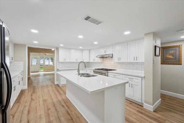 3533 Fm 563, Anahuac, TX 77514 - kitchen featuring under cabinet range hood, stainless steel gas range oven, light wood-style flooring, freestanding refrigerator, and light countertops