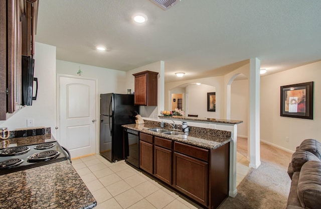 22418 Threefold Ridge Dr, Hockley, TX 77447 - kitchen featuring black appliances, dark stone countertops, light tile patterned floors, open floor plan, and a peninsula