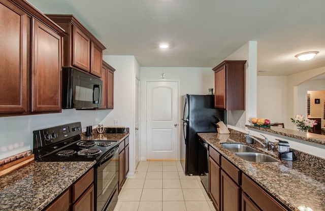 22418 Threefold Ridge Dr, Hockley, TX 77447 - kitchen featuring black appliances, dark stone counters, light tile patterned floors, and arched walkways