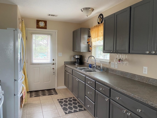 1025 14th St, Dickinson, TX 77539 - kitchen with freestanding refrigerator, healthy amount of natural light, light tile patterned floors, and dark countertops