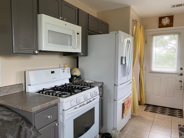 1025 14th St, Dickinson, TX 77539 - kitchen with white appliances, light tile patterned floors, dark countertops, and gray cabinetry