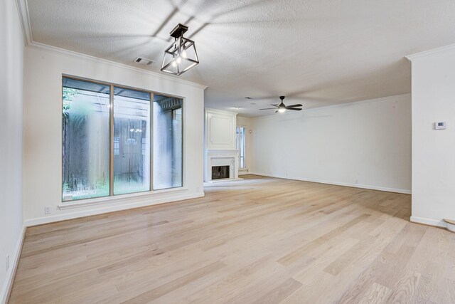 2308 Nantucket Dr Unit B, Houston, TX 77057 - unfurnished living room featuring ceiling fan, crown molding, light wood-style flooring, a textured ceiling, and a fireplace with raised hearth