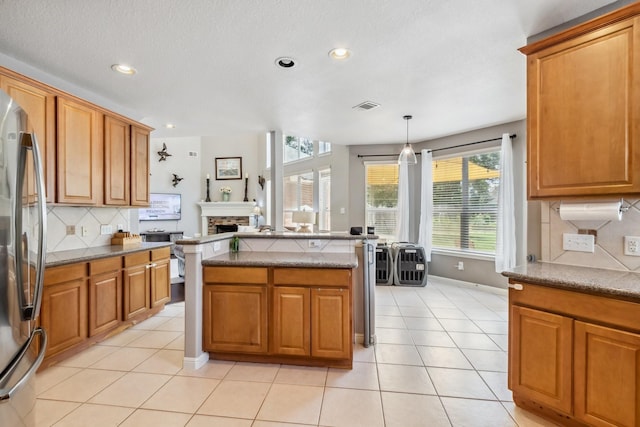 13518 Via Chianti Ln, Cypress, TX 77429 - kitchen with stainless steel fridge, a fireplace, brown cabinets, and recessed lighting