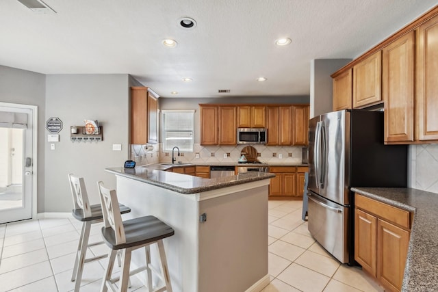 13518 Via Chianti Ln, Cypress, TX 77429 - kitchen featuring stainless steel appliances, light tile patterned floors, a kitchen bar, backsplash, and recessed lighting