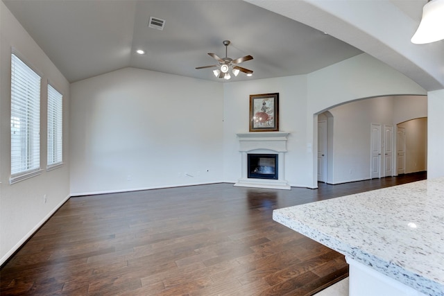 24014 Bluestem Ridge Ct, Katy, TX 77493 - unfurnished living room with a ceiling fan, a glass covered fireplace, lofted ceiling, dark wood finished floors, and arched walkways
