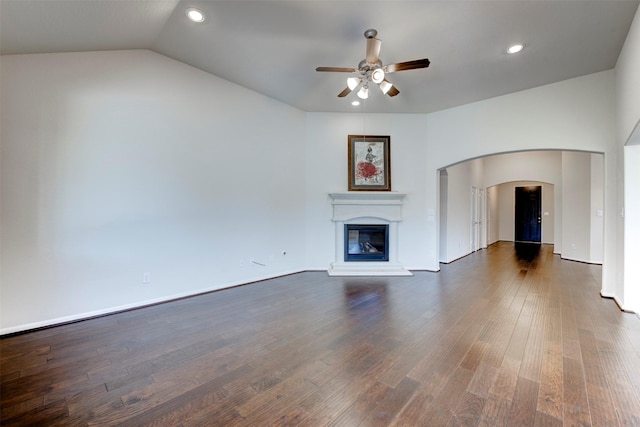 24014 Bluestem Ridge Ct, Katy, TX 77493 - unfurnished living room featuring ceiling fan, a glass covered fireplace, dark wood finished floors, recessed lighting, and arched walkways