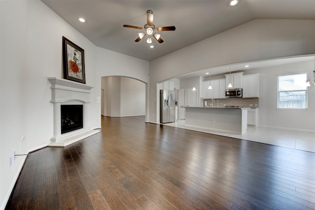 24014 Bluestem Ridge Ct, Katy, TX 77493 - unfurnished living room featuring a ceiling fan, vaulted ceiling, wood finished floors, a fireplace with raised hearth, and recessed lighting