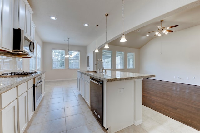 24014 Bluestem Ridge Ct, Katy, TX 77493 - kitchen with appliances with stainless steel finishes, recessed lighting, an island with sink, white cabinetry, and light stone counters