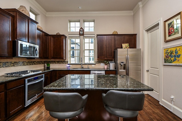 10924 Wrenwood Park, Houston, TX 77043 - kitchen with stainless steel appliances, backsplash, dark wood-style floors, crown molding, and a breakfast bar area