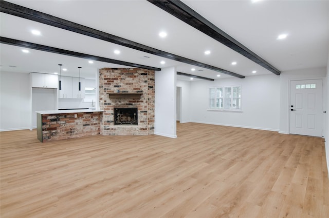 12706 Westleigh Dr, Houston, TX 77077 - unfurnished living room featuring beamed ceiling, light wood finished floors, recessed lighting, and a fireplace