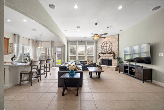 3822 Moreland Branch Ln, Katy, TX 77493 - living area featuring recessed lighting, a ceiling fan, arched walkways, a stone fireplace, and light tile patterned floors