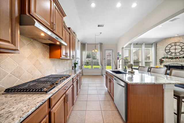 3822 Moreland Branch Ln, Katy, TX 77493 - kitchen with under cabinet range hood, appliances with stainless steel finishes, a breakfast bar area, tasteful backsplash, and light stone counters