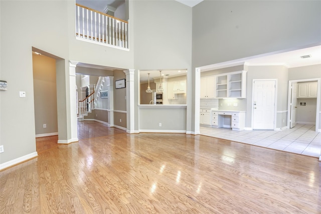 3718 W Pine Brook Way, Houston, TX 77059 - unfurnished living room with decorative columns, a towering ceiling, light wood finished floors, stairs, and ornamental molding