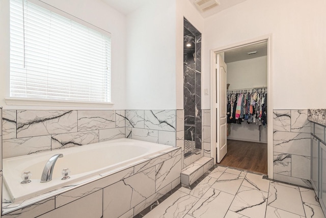 30110 Saw Oaks, Magnolia, TX 77355 - bathroom with marble finish floors, a bath, tiled shower, a walk in closet, and a wainscoted wall