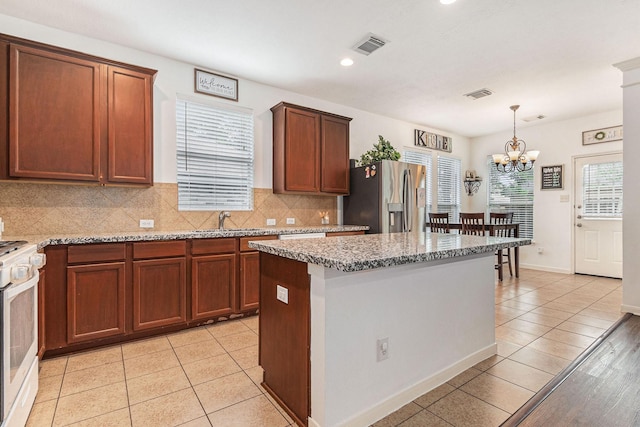 30110 Saw Oaks, Magnolia, TX 77355 - kitchen featuring stainless steel fridge with ice dispenser, white range with gas stovetop, light tile patterned floors, tasteful backsplash, and a chandelier